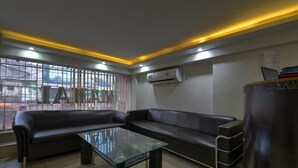 Een modern wachtgedeelte met een leren bank, een glazen salontafel en een airconditioner aan de muur.
