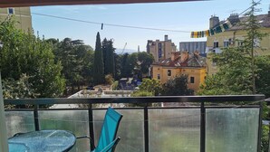 A balcony with a table and chairs, overlooking a cityscape with buildings and trees. - Apartment Budin 2 Rijeka City Center (Rijeka)