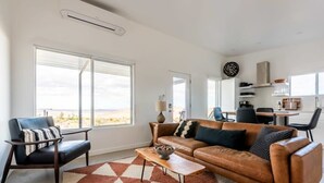 A modern living room with a leather sofa, a coffee table, and a patterned rug. - Sunset Heights By Homestead Modern (Joshua Tree)