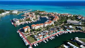 An aerial view of a coastal resort with multiple buildings, a marina, and a clear view of the ocean. - Ocean Front Marina Sub Penthouse (Punta Cana)