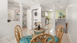 A modern kitchen with a washing machine, a dining area with a table and chairs, and a view into the living area. - THE PELICAN PEARL ~ Charming 2 BR/1 Ba Condo in Truman Annex! (Key West)