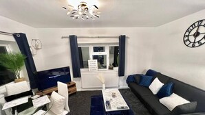 A modern living room with a sofa, armchairs, a coffee table, and a TV. - Beautiful 2-bed House in Watford (Watford)