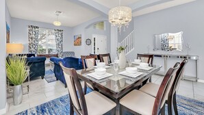 A dining area with a glass table set for six, surrounded by wooden chairs. - Stylish 6 bedroom! Near Disney! with private pool! (Kissimmee)