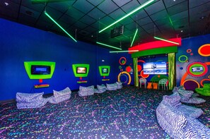 A room with neon lights, multiple screens, and colorful patterns on the floor and walls.