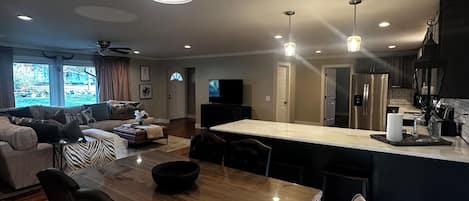 A modern living room with a wooden dining table, black leather chairs, and a zebra-patterned bench.