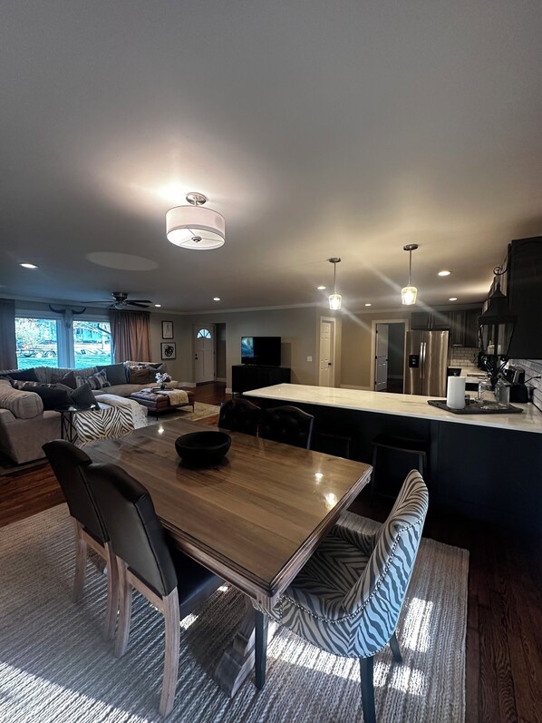 A modern living room with a wooden dining table, black leather chairs, and a zebra-patterned bench.