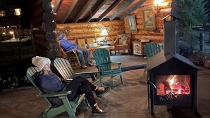 Un espace extérieur aménagé avec des chaises Adirondack, un foyer et une structure en bois dotée d’un toit incliné.
