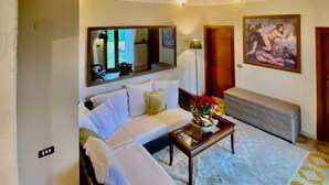 Un salon avec un canapé blanc, une table basse en verre et un tableau accroché au mur.