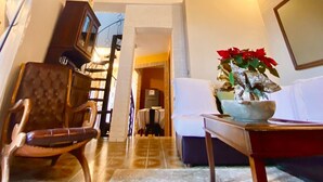 Une pièce avec un haut plafond en bois, un lustre, un canapé, un fauteuil, une table avec une plante et un miroir au mur.