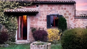 Une maison en pierre avec un toit de tuiles, une porte en bois et une fenêtre avec des volets.