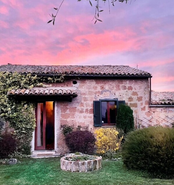 Una casa de piedra con techo de tejas, puerta de madera y ventana con contraventanas.