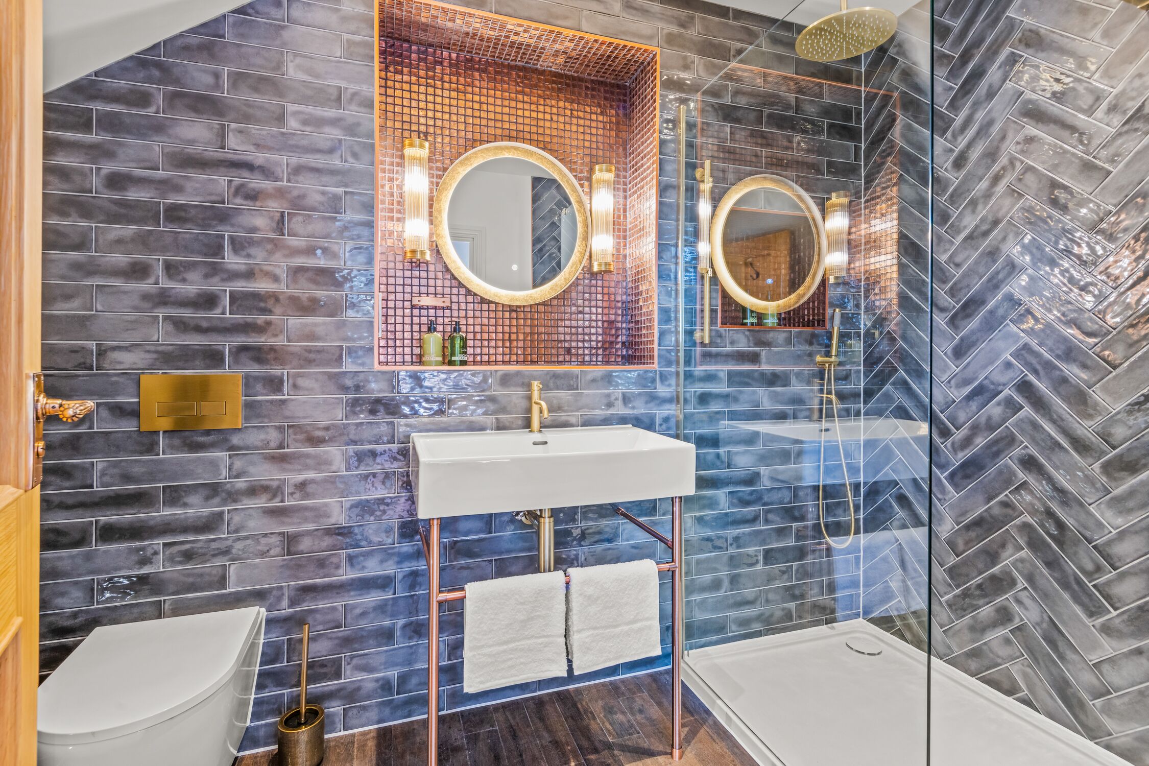 A modern bathroom with a large mirror, two sinks, and a glass shower enclosure.