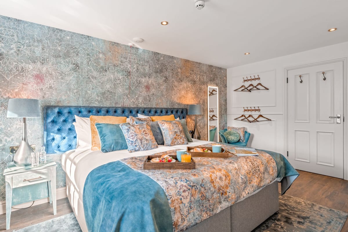 Quarto com uma cama grande, mesa de cabeceira, espelho e guarda-roupa.