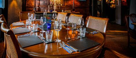 A dining table set for six with chairs, a chandelier, and wall-mounted lamps.
