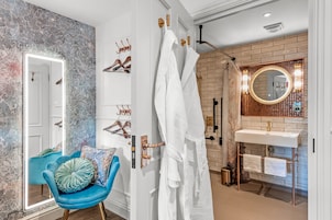 A bathroom with a white vanity, a round mirror, and a shower area with a glass door.
