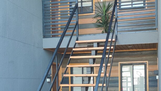 A multi-level building with a wooden exterior, a metal staircase, and a small balcony with a toy car.