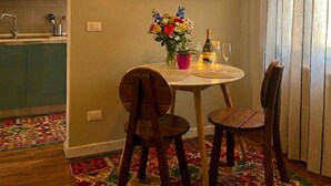 Ein Essbereich mit einem runden Tisch, zwei Stühlen, einer Blumenvase, einer Flasche und einem Glas.