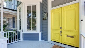 A two-story house with a porch, a yellow door, and a welcome mat. - Hall Street Inn, Relaxing | Historic | Fresh (Savannah)