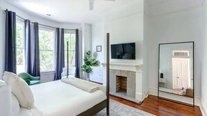 A bedroom with a bed, a TV, a fireplace, and a large mirror. - Hall Street Inn, Relaxing | Historic | Fresh (Savannah)