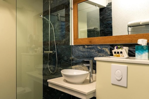 A modern bathroom with a glass-enclosed shower, a white sink, and a marble backsplash. - Royal Breeze Hotel NV (Paramaribo)