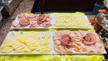 A buffet table with various food items including sliced meats and cheeses.