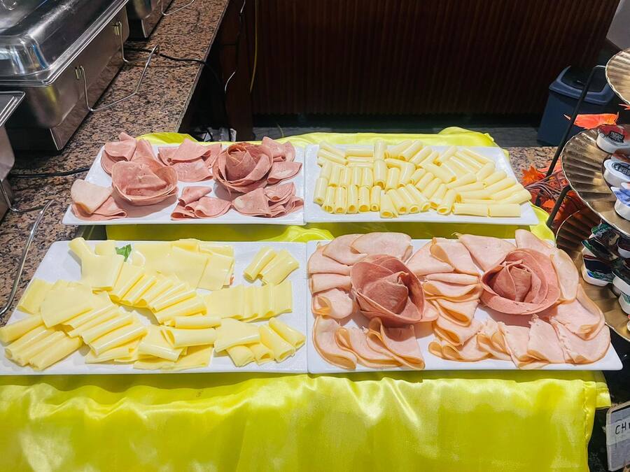 A buffet table with various food items including sliced meats and cheeses.