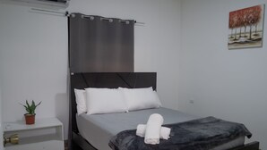 A modern bedroom with a bed, a potted plant, a bedside table, and a wall-mounted air conditioner. - Apartment Pinilla With 2 Room, Kitch, a/c (Pinilla)
