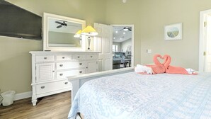 Un dormitorio con cama, cómoda, espejo y ventilador de techo.