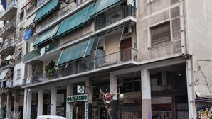 Ein mehrstöckiges Gebäude mit Balkonen, einem Schaufenster und parkenden Autos.