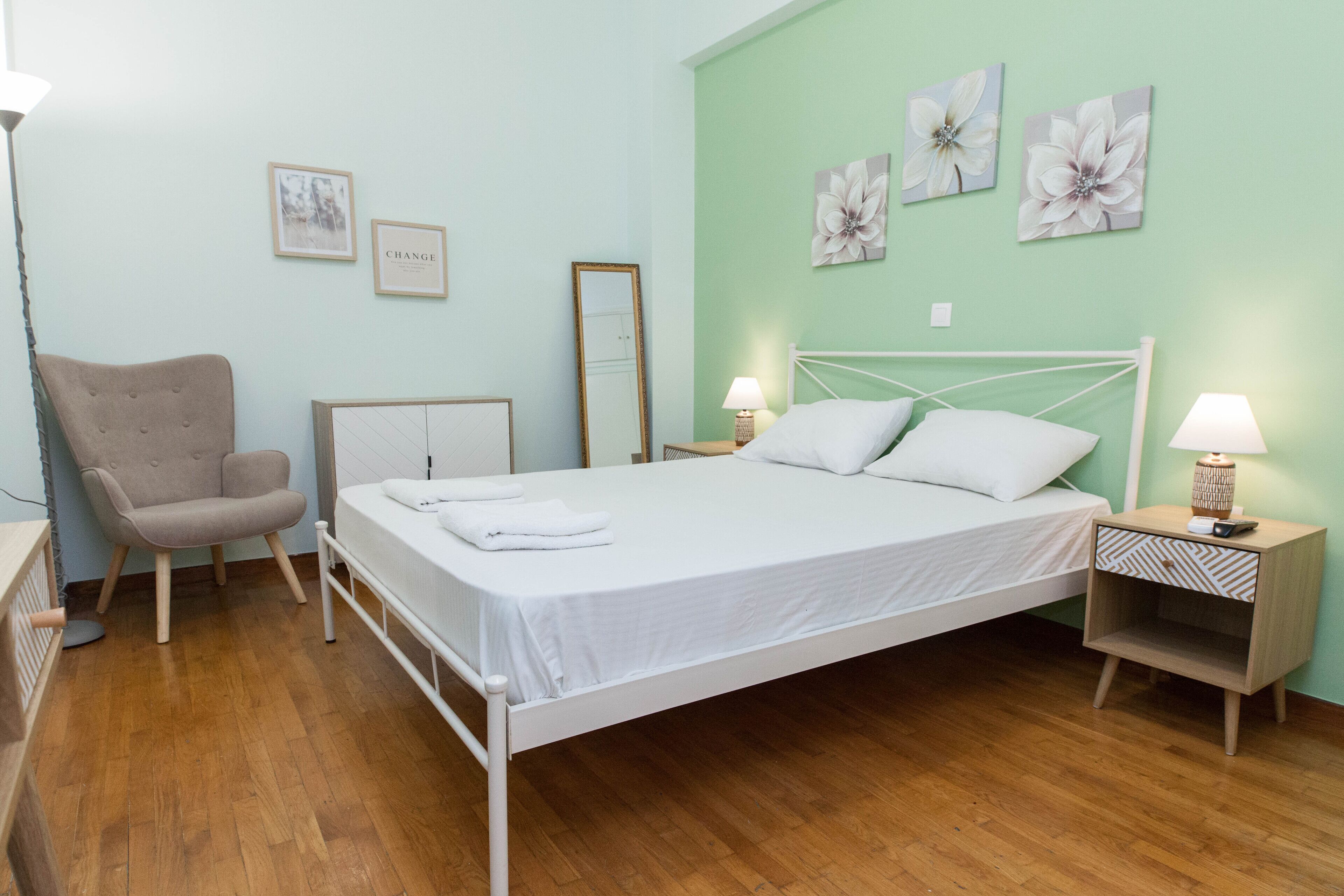 Ein Schlafzimmer mit Bett, Sessel, Nachttisch und Wandbildern.