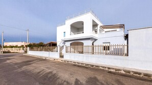 A modern white building with a gated entrance, a balcony, and a clear sky. - 3700 La Spiaggetta - Bilo Lato by Barbarhouse (Porto Cesareo)