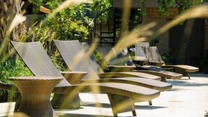 Outdoor lounge chairs with woven seats and backs, arranged on a patio with a building in the background. - Dream House | 2BR Near Galleria (Houston)