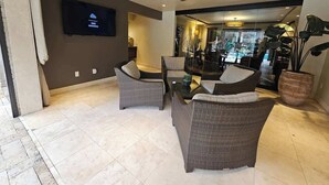 A modern living area with wicker furniture, a flat-screen TV, and a ceiling fan. - Dream House | 2BR Near Galleria (Houston)