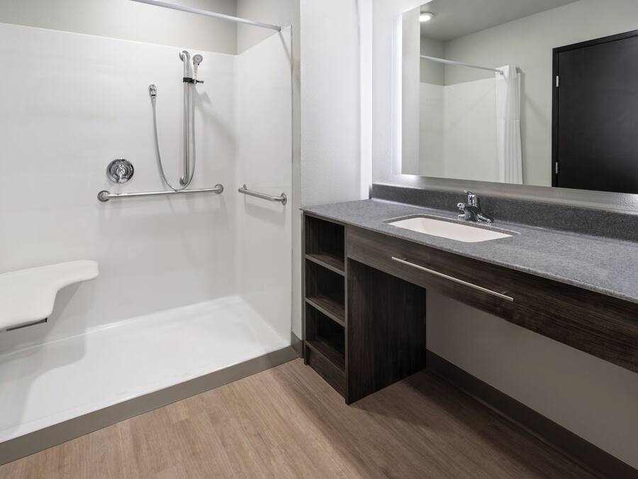 Een moderne badkamer met een douche, wastafel en spiegel.