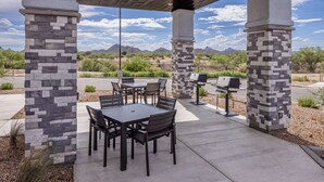 An outdoor patio with stone pillars, a table and chairs, and a grill. - My Place Hotel-Tucson North/Marana/Cortaro, AZ (Tucson)