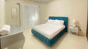 A bedroom with a bed, bedside tables, a desk, and a curtain.