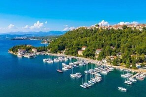 A coastal town with a marina filled with boats, surrounded by lush greenery and a clear blue sky. - Beautiful Apartment in Villa Vuka in Omišalj (Omisalj)