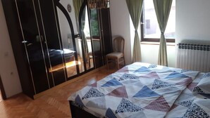 Un dormitorio con cama, armario, silla y ventana con cortinas.