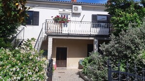 Un edificio de dos pisos con un balcón, una puerta y una escalera.