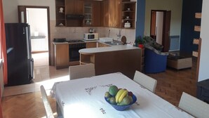 Una cocina compacta con armarios de madera, una isla central y una zona de comedor con una mesa dispuesta para dos.