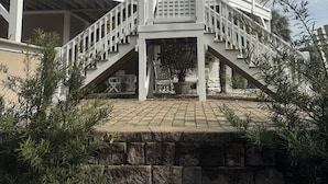 Ein zweistöckiges Haus mit überdachter Veranda, einer Treppe und einer Steinmauer.