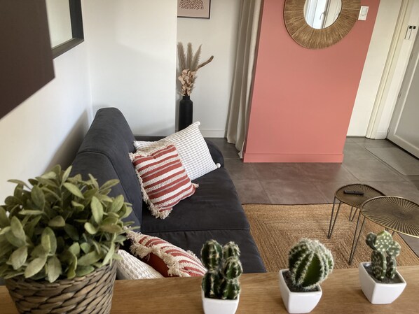 A modern living room with a dark grey sofa, white and red striped pillows, a woven plant pot, and three potted cacti. - Les Mirandelles - Vue/accès lac (Le Bourget-du-Lac)