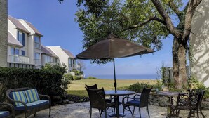 Eine Terrasse im Freien mit Tisch und Stühlen, einem gestreiften Sofa und einem großen Sonnenschirm.