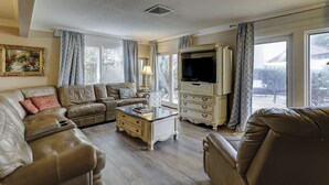 Ein Wohnzimmer mit einer Ledersofa, einem Couchtisch, einem Fernseher und einer Kommode.