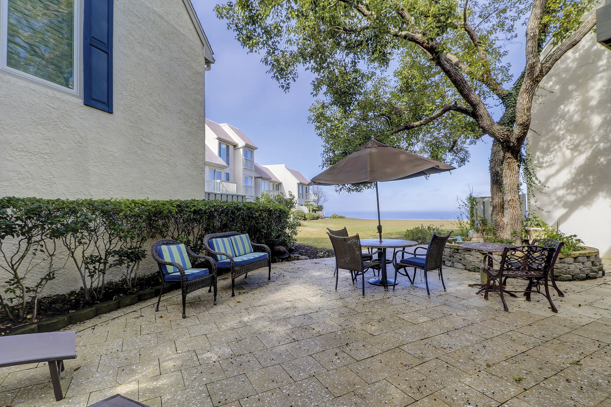 An outdoor patio with wicker furniture, a table, and an umbrella.