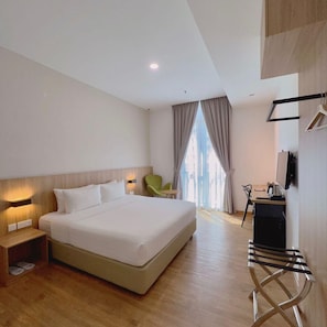 A modern hotel room with a large bed, bedside table, a desk with a chair, a green chair, and a view through the window. - S Hotel (Johor Bahru)