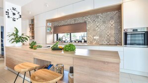 A modern kitchen with a wooden island, bar stools, a Bosch oven, and a patterned backsplash.