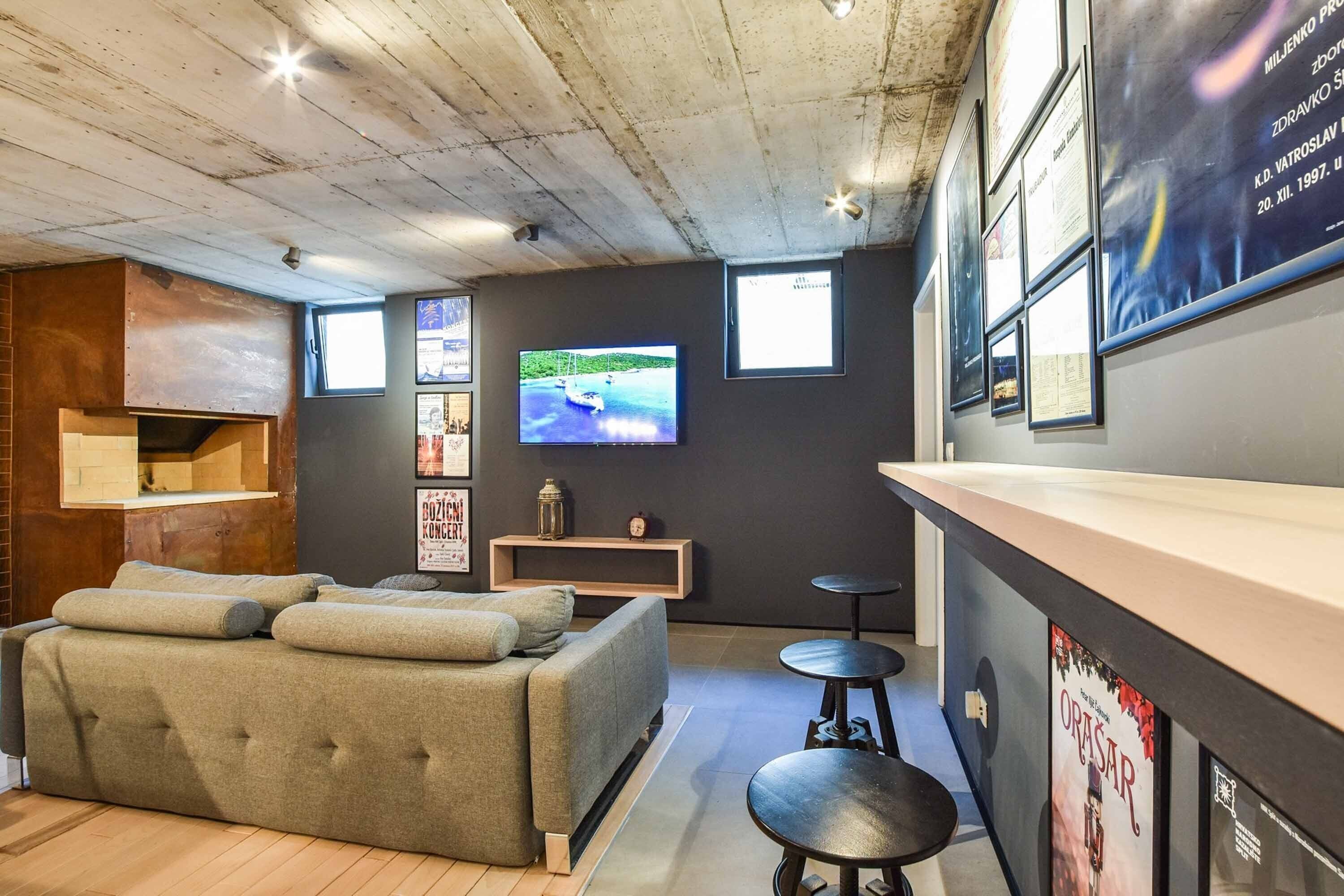 Ein modernes Zimmer mit einer Couch, einem Fernseher, einer Bar und einer Holzbalkendecke.