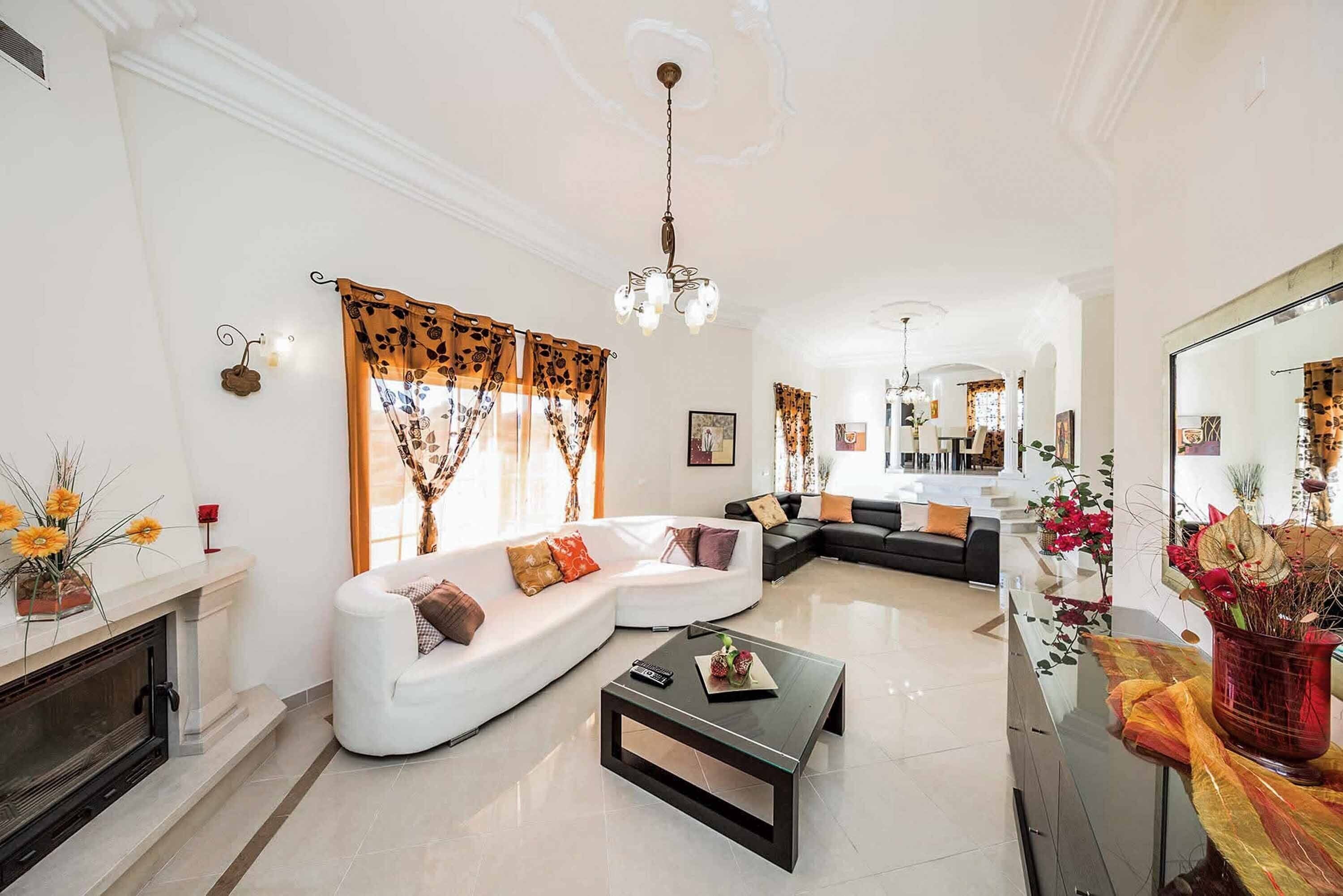 A spacious living room with a white sectional sofa, a black coffee table, and a fireplace.