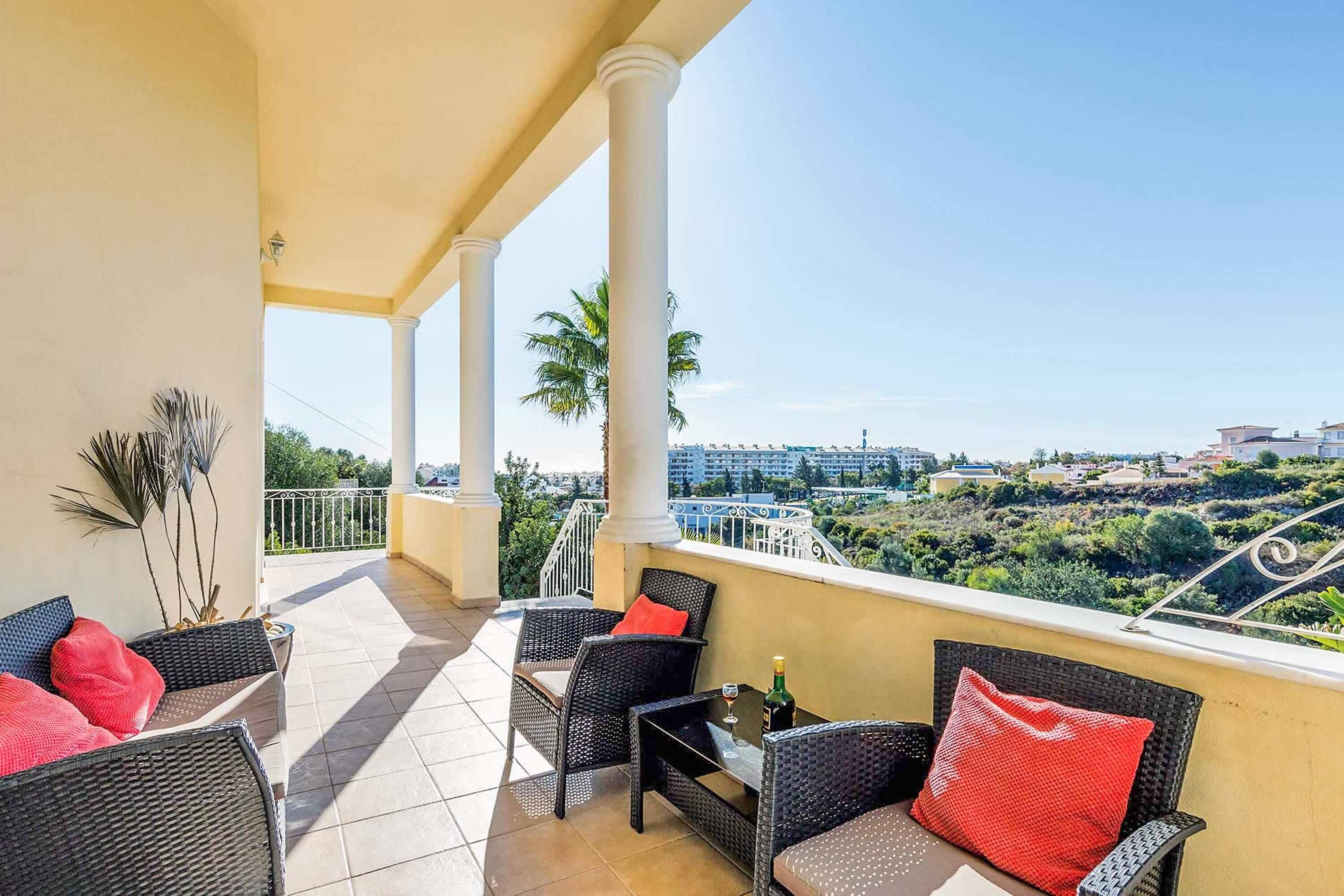 A balcony with wicker furniture, a table, and a bottle of champagne.